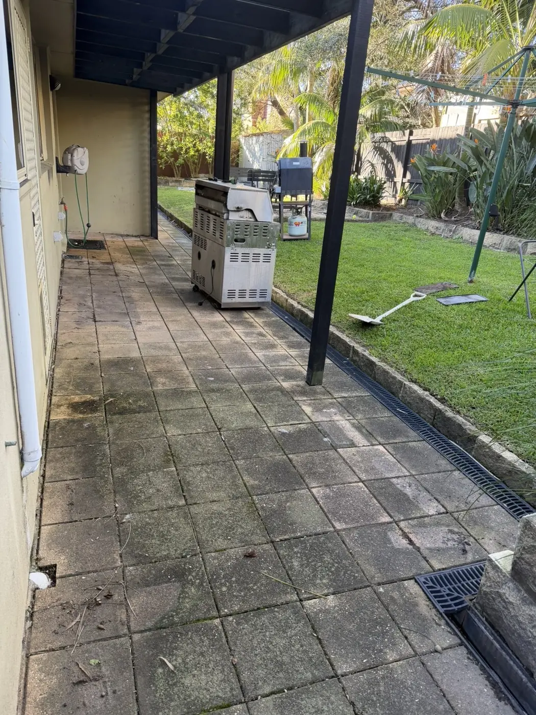 Paved pergola entertaining area dark with grime and mould before cleaning