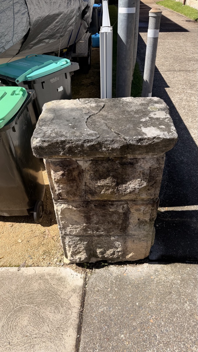 Sandstone pillar covered in black mould before cleaning
