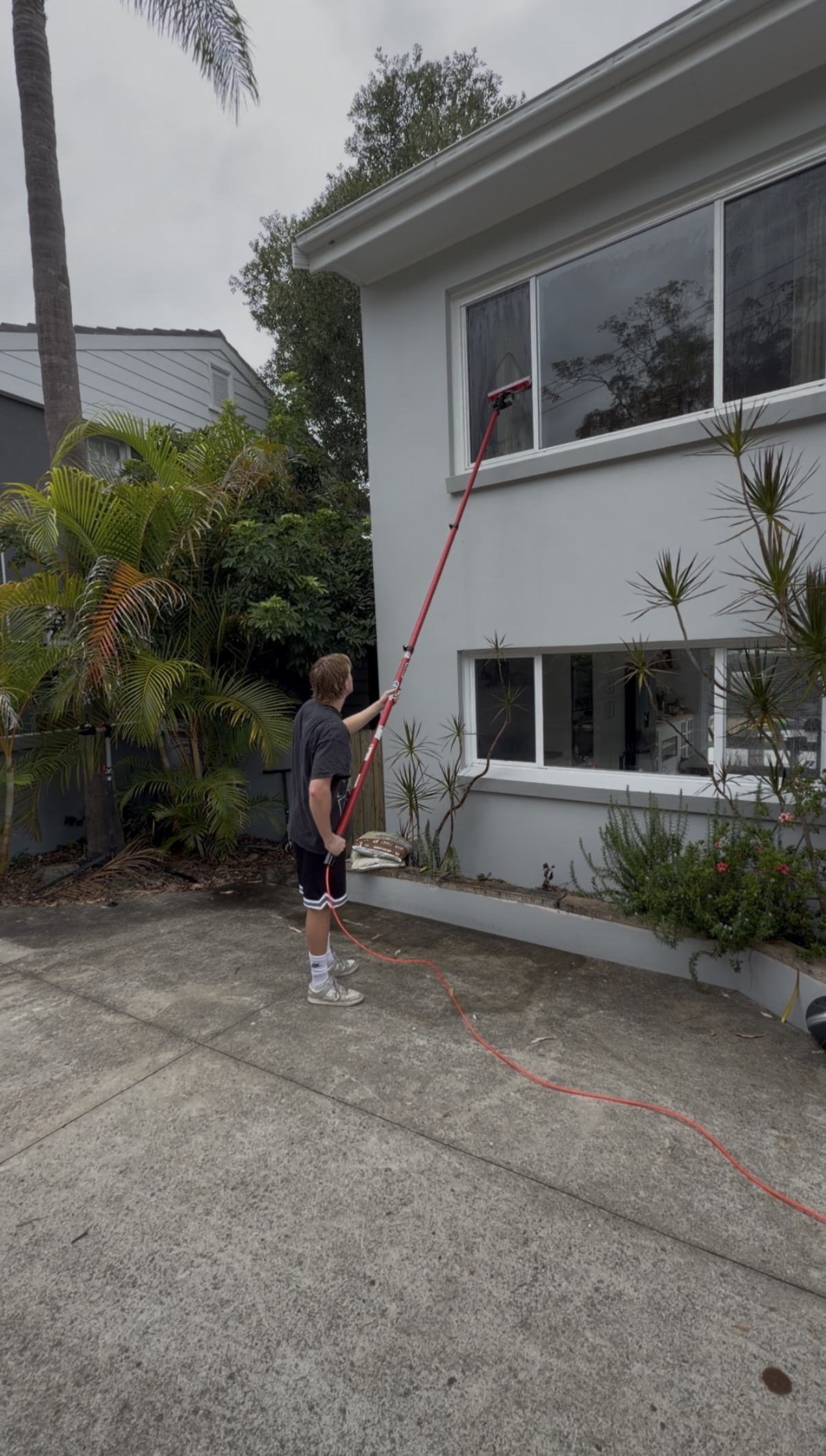 Window cleaning brick house second storey with water-fed pole
